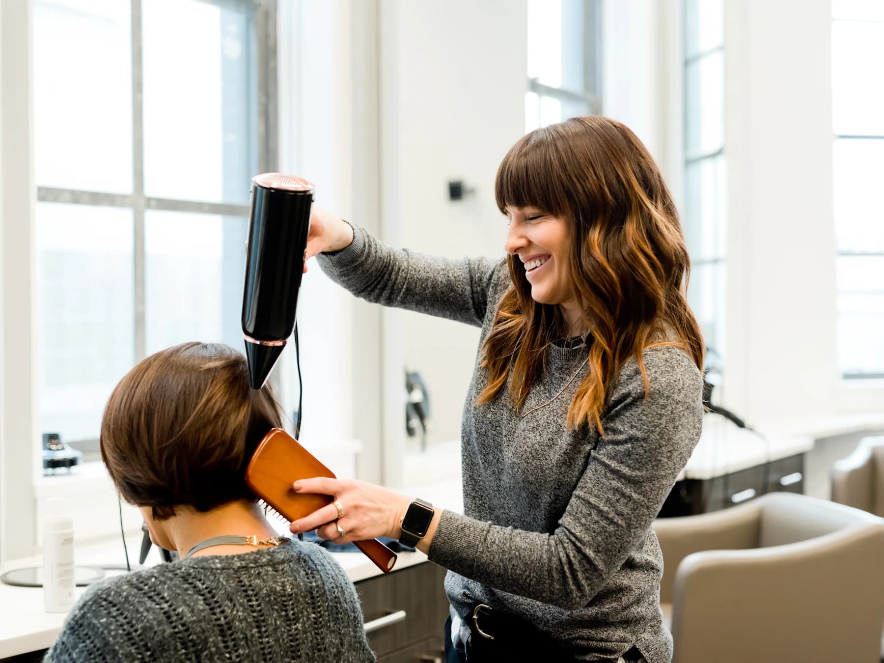 Coiffeuse réalisant une prestation auprès d'une cliente en salon